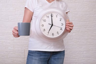 Saat 07: 00 'yi ve bir fincan kahveyi gösteren serbest çalışan bir kadın uzaktan ve uzak çalışma konsepti boyunca dakiklik..