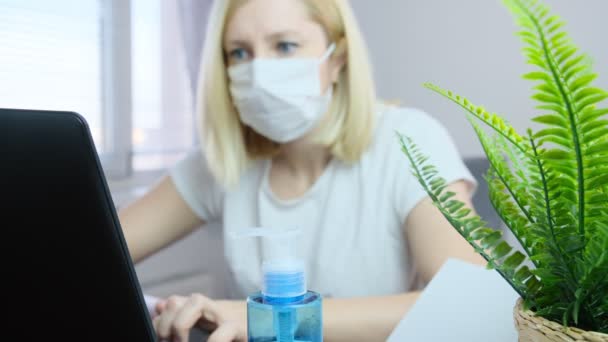 在家里的笔记本电脑上工作着面容模糊的女自由撰稿人 在她面前的桌子上摆着手部清洁剂作为保护 — 图库视频影像