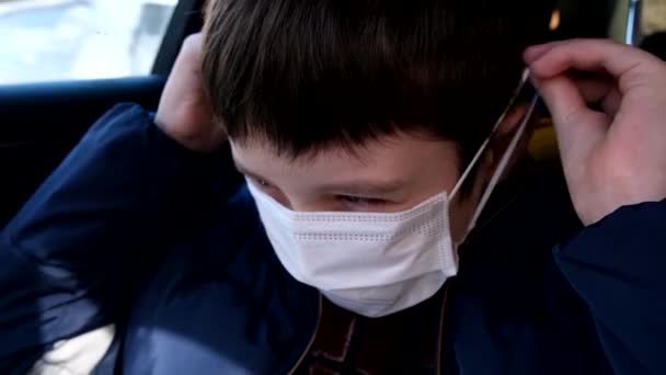 一个十几岁的男孩在车上戴着白色防护外科口罩 作为对病毒感染的防护 防止考拉病毒 系数19的概念 — 图库视频影像