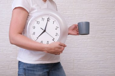 Saat 07: 00 'yi ve bir fincan kahveyi gösteren serbest çalışan bir kadın uzaktan ve uzak çalışma konsepti boyunca dakiklik..