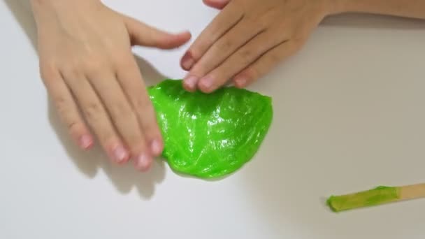 一个男孩玩绿色黏液，孩子们的运动技巧，创造力和发展，流行的抗压玩具 — 图库视频影像