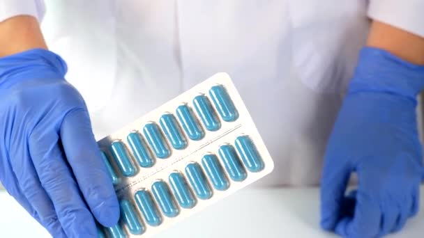 Врач в синих перчатках показывает таблетки, капсулы в волдырях, лечение заболеваний и рецепты концепции — стоковое видео
