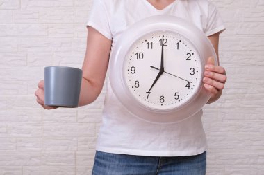 Saat 07: 00 'yi ve bir fincan kahveyi gösteren serbest çalışan bir kadın uzaktan ve uzak çalışma konsepti boyunca dakiklik..