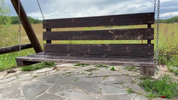 Grande balançoire en bois vacante allant et venant dans un payssyde en été, pelouse d'herbe verte sur fond, nostalgie et vue mélancolique 
