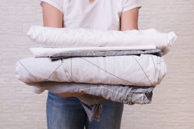 Kadın ev hanımı bir yığın katlanmış çarşaf tutuyor. Çamaşır ve çarşaf yıkama, temizlik konsepti.