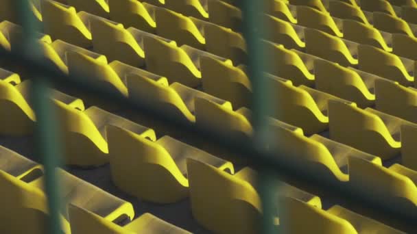 Gula stolar i en tom stadium bakom en metall staket, Slowmotion 120fps — Stockvideo