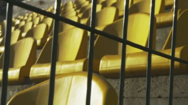 Sarı koltukları arkasında bir metal çit, ağır çekim 120fps bir boş Stadyumu