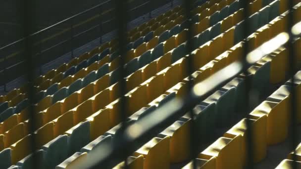 Cadeiras amarelas em um estádio vazio atrás de uma cerca de metal, câmera lenta 120fps — Vídeo de Stock