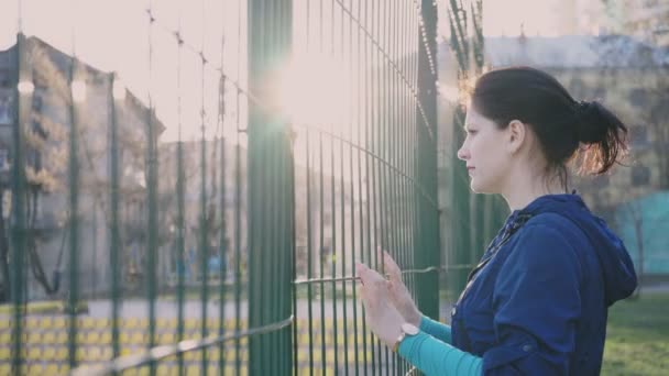 Chica mirando desde detrás de una valla, 4k — Vídeos de Stock