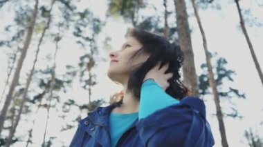 Bir parkta genç bir çekici kadın gülümsüyor ve saçlarını 4 k ile çalış