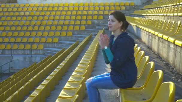 Una ragazza siede nella tribuna dello stadio, 4k — Video Stock