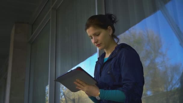 Молодая женщина с табличкой у окна дома, 4k — стоковое видео