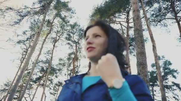 Een jonge aantrekkelijke vrouw in een park glimlacht en speelt met haar haar, 4k — Stockvideo