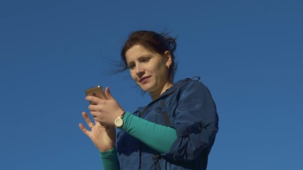 Mujer joven navegando por Internet en el teléfono y charlando al aire libre. cámara lenta, 120 fps — Vídeos de Stock