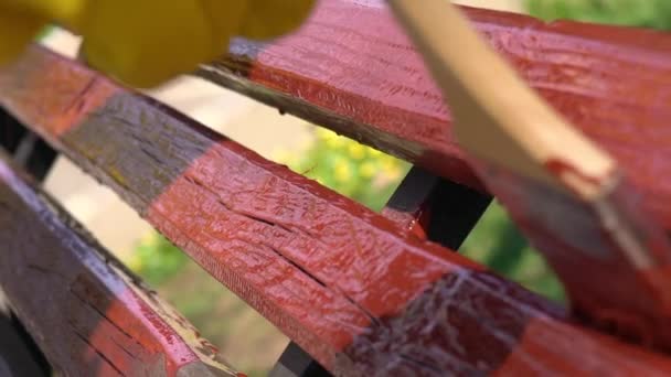 Detail ruky v žluté ochranné rukavice malířské dřevěné prkno s štětec štětce v červené barvě, pomalý pohyb — Stock video