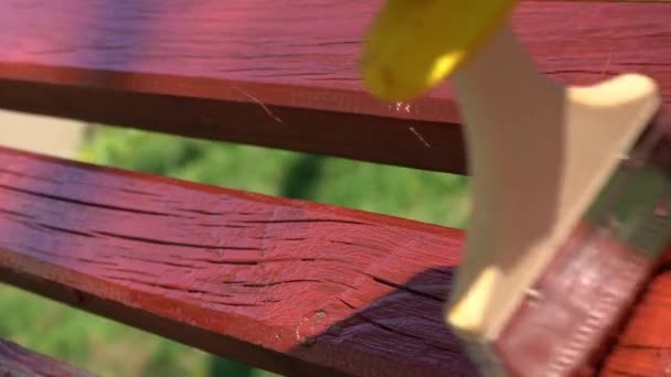 Γκρο πλαν του χεριού σε κίτρινο προστατευτικό γάντι ζωγραφική ξύλινη σανίδα με βούρτσα πινέλο σε κόκκινο χρώμα, αργή κίνηση — Αρχείο Βίντεο