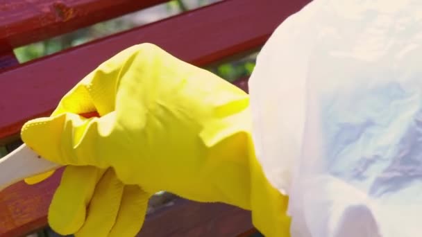 Close-up van de hand in gele beschermende handschoen schilderen houten plank met penseel borstel in rode kleur, slow-motion — Stockvideo
