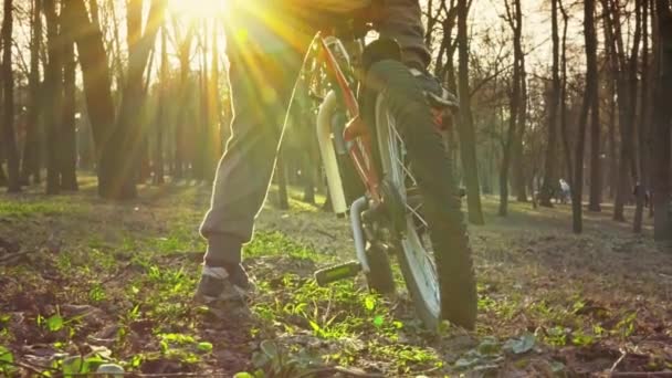 Menino aprende a andar de bicicleta no parque, pôr-do-sol, câmera lenta — Vídeo de Stock