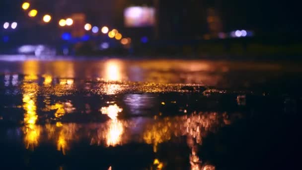 Les voitures roulent dans de grandes flaques d'eau sur la route de nuit dans la ville, les flaques d'eau pulvérisées se dispersent sous les roues de la voiture — Video