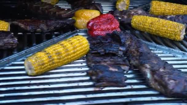 Ребра ягненка и овощи на вращающемся гриле, мясо и кукуруза на барбекю, замедленная съемка — стоковое видео