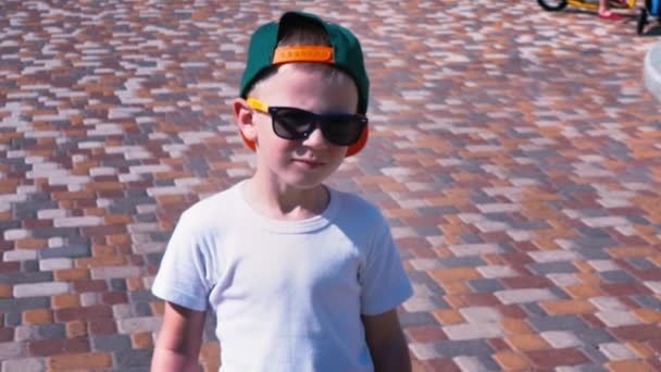 Mladík v sluneční brýle a čepici na ulici, dítě 6 let staré dítě chůze, zpomalené — Stock video