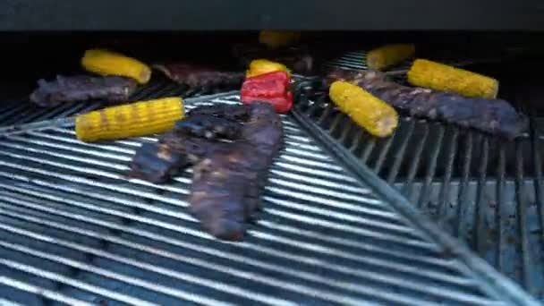 Ребра ягненка и овощи на вращающемся гриле, мясо и кукуруза на барбекю, 4K — стоковое видео