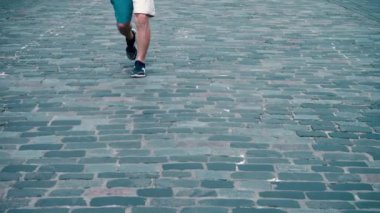 Bir adam yaşlı bir koşucu bir maraton, bacaklar yakın çekim yer aldığı bir taş döşeli şehir yol boyunca çalışır