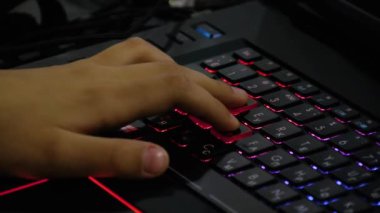 Genç bir çocuk onun kişisel bilgisayarda bir online oyun oynarken. Onun el ve parmak klavye düğmelere basmaya yakın çekim