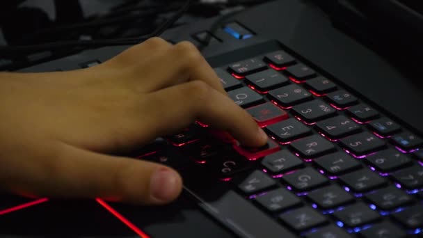 Молодий хлопець грає в онлайн гру на своєму персональному комп'ютері. Крупним планом на руці і пальцях, натискаючи кнопки клавіатури — стокове відео