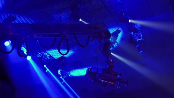 テレビ番組を撮影するときにタップ上のビデオカメラ ライブコンサート 天井の下の観客の上にカメラの動き 高さから撮影 スポットライトがシーンを照らします 青い光 — ストック動画