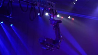 Bir televizyon programı çekilirken musluktaki video kamera. Canlı konser. Kameranın tavanın altındaki seyircilerin üzerindeki hareketi. Yüksekten ateş ediyorlar. Sahne ışıkları sahneyi aydınlatır. Mavi ışık.