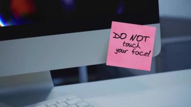 Yüzüne dokunma. Monitördeki çıkartmadaki yazı. Mesaj var. Motivasyon. Hatırlatma. El yazısı bir kalemle yazılmış. Renkli çıkartma. Bir çalışana, bir meslektaşa mesaj var.. 