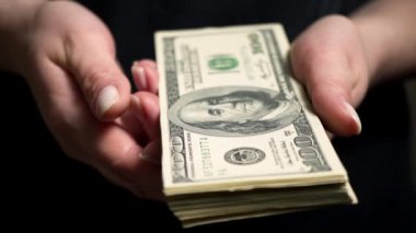 Bir kadın elinden yüz dolarlık banknot alır. Bir kadın bir paket Amerikan doları tutuyor. Para birimi operasyonları. - Para kaybı. İflas. Finansal kriz. Borsada oynuyorum..