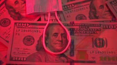 Benjamin Franklin için ilmek. 100 dolarlık banknot bir döngüde. Küresel ekonomik kriz. Bir tıbbi maske dolarların üzerinde yatar. Pandemik virüs. Finansal kriz. Kırmızı renk, tehlike. İşsizlik parası. COVID-19