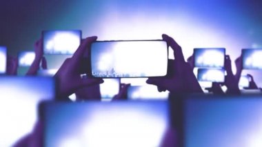 Hayranlar akıllı telefonlardan video kaydediyor. Bir sürü akıllı telefon. Canlı yayın. Hikayeler. Kalabalık bir konser izliyor, şarkı söylüyor, zıplıyor. Çarpıcı sahne ışıkları. Müzik konsepti. Mutlu insanlar inanılmaz bir müzik konseri izliyorlar.. 