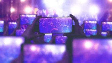 Hayranlar akıllı telefonlardan video kaydediyor. Bir sürü akıllı telefon. Canlı yayın. Hikayeler. Kalabalık bir konser izliyor, şarkı söylüyor, zıplıyor. Çarpıcı sahne ışıkları. Müzik konsepti. Mutlu insanlar inanılmaz bir müzik konseri izliyorlar.. 