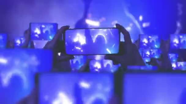 群衆はコンサートを見て 飛び跳ねる コンサート中に空中に浮かぶ金のコンフェッティ ファンはスマートフォンでビデオを録画しています 多くのスマートフォン ライブストリーム 舞台光を撫でる — ストック動画