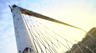 Bir futbol kalesine yakın çekim. Parlak güneş ağların arasından parlıyor. 