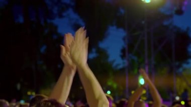 İnsanlar konserde alkışlıyorlar. Avuç içlerini aydınlatın. Mutlu insanlar inanılmaz bir müzik konseri izliyorlar. Neşeli hayranlar zıplıyor ve ellerini kaldırıyor. Taraftarlar akıllı telefondan bir konser çekiyorlar.