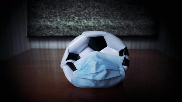 戴着医用面罩的球靠近空闲的电视 足球赛取消了 世界流行病 取消大规模活动 重新安排足球锦标赛 Coronavirus 没有图像的电视 烦躁不安的粉丝Glitch — 图库视频影像