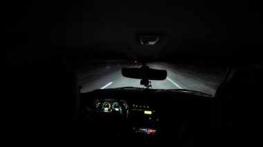 Sürücü aydınlık bir yolda gece at sürüyor. Araba çatlıyor ve sendeliyor. İçeriden. Kontrol paneli, radyo, DVR. Sollama. Yaklaşan arabaların gözleri kör olur. Farlar yolu aydınlatır. Yol işaretleri ve işaretleme