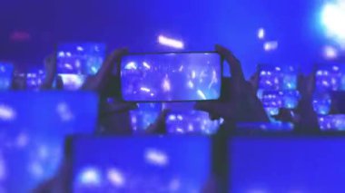 Kalabalık bir konser izliyor, şarkı söylüyor, zıplıyor. Konser sırasında havada yüzen altın konfetileri. Hayranlar akıllı telefonlardan video kaydediyor. Bir sürü akıllı telefon. Canlı yayın. Hikayeler. Sahne ışığı.