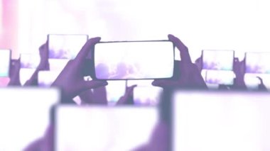 Kalabalık bir konser izliyor, şarkı söylüyor, zıplıyor. Çarpıcı sahne ışıkları. Mutlu insanlar. Müzik konsepti. Hayranlar akıllı telefonlardan video kaydediyor. Bir sürü akıllı telefon. Canlı yayın. Hikayeler.