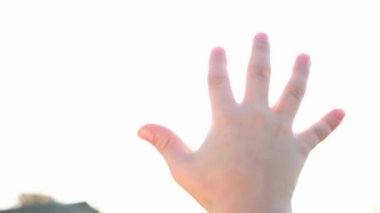 Bir çocuk ellerinin arasından parlak güneşe bakar. Güneşin sihirli ışınları parmaklarının arasından parlıyor. Muhteşem parlak ışık. Flaş. Güneşin tadını çıkaran bir çocuk. Dikkatsizlik işte. Mutluluk. Turizm.