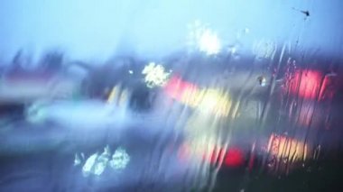 Trenin camında yağmur damlaları. Demiryolu. Bulanık şehir trafiği. Sokak lambaları. Seyahat konsepti. Gözyaşları. Üzüntü. Pencerenin dışındaki manzara. Demiryolu raylarını taşıyorum. Kötü hava. Trenle seyahat etmek.