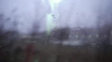 Pencerede yağmur damlaları. Demiryolu. Bulanık şehir trafiği. Sokak lambaları. Seyahat konsepti. Gözyaşları. Üzüntü. Pencerenin dışındaki manzara. Demiryolu raylarını taşıyorum. Kötü hava. Trenle seyahat etmek.