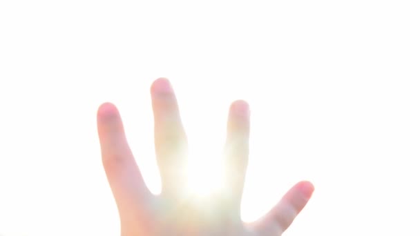 一个小孩通过他的手看着明亮的太阳 阳光的神奇光芒透过你的手指闪耀 非常明亮的光 闪光灯 一个在阳光下晒太阳的孩子粗心 旅游业 — 图库视频影像