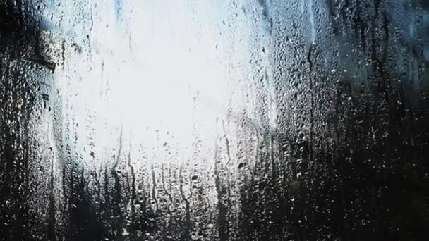 雨滴从玻璃上流下来 阳光穿过潮湿的窗户 多雾的窗户 窗户在融化 雨窗里的晨阳 春暖化 — 图库视频影像