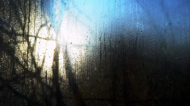 雨滴がガラスの下を流れる 湿った窓から太陽 フォギーウィンドウを閉じます 窓が溶けている 雨の窓の朝の太陽 春の温暖化 — ストック動画
