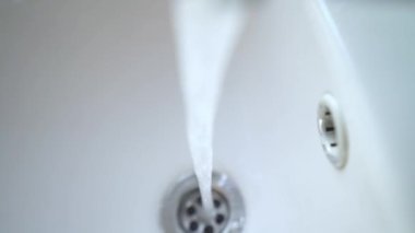 Musluktan su dökülüyor. Musluktan lavaboya akan soğuk su, yakın plan. Su kaynağı. Coronavirus seyahat önleme sabunla el yıkama. Temiz su eksikliği, dikkatsizce kaynak kullanımı..